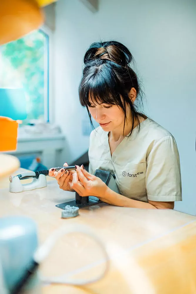 Zentrum für Zahnmedizun Labor Frau bemalt Zahnersatz