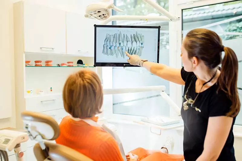 Zahnarzt Zahnimplantate forst42 Beratung Patientin und Visualisierung eines Scans am Bildschirm